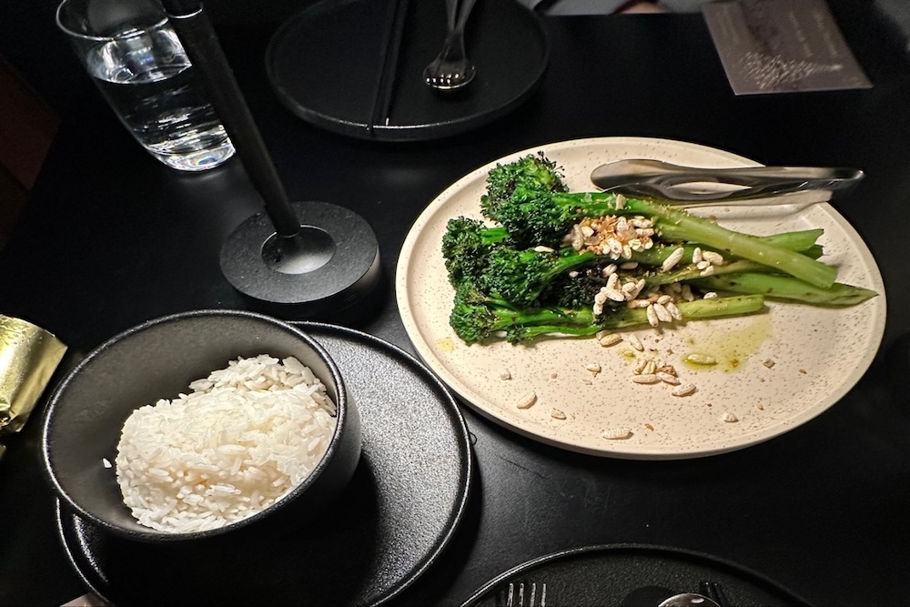 Charred broccolini side dish with salt seasoning served on a black plate in Q Dining Canberra