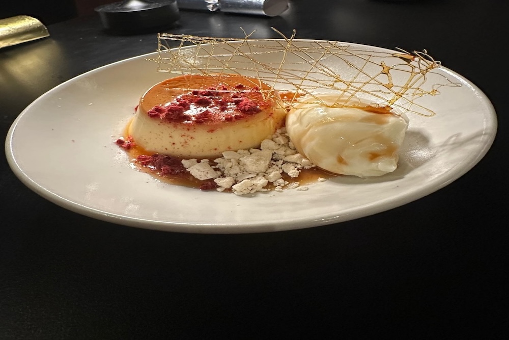 Caramel Coffee Flan dessert with coconut ice cream, raspberries, and spun sugar garnish