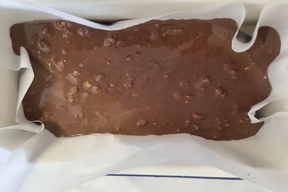 Rice flour brownie batter poured into lined baking dish